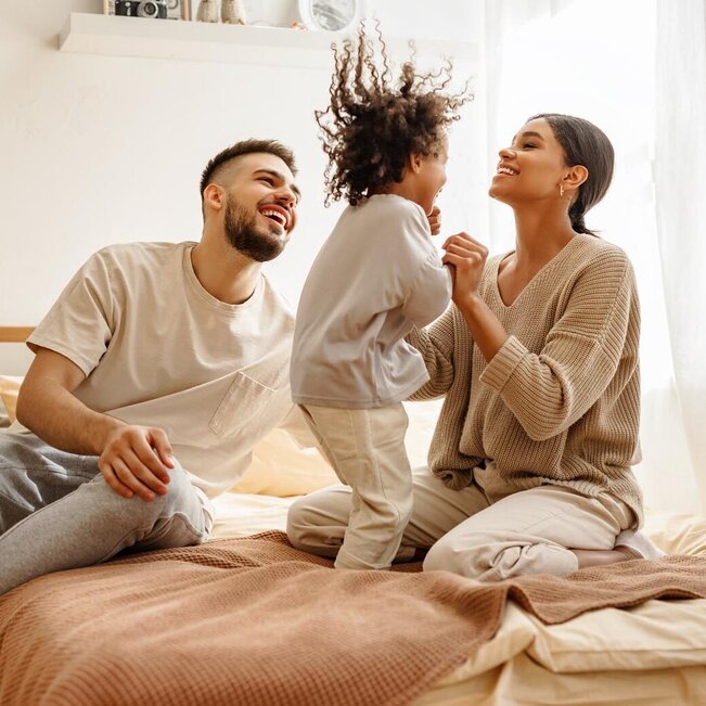 Mother and father playing with child on the bed